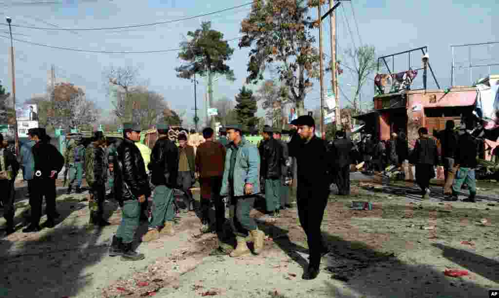 Afghan police forces and civilians inspect the site of a suicide attack in Maimana, Faryab province, Afghanistan, March 18, 2014.