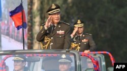 FILE - Cambodian Prime Minister Hun Sen (L) salutes, along with his son, Lt. Gen. Hun Manet (background) during an inspection of troops at a ceremony in Phnom Penh, Cambodia, Jan. 24, 2019. (Handout via AFP)