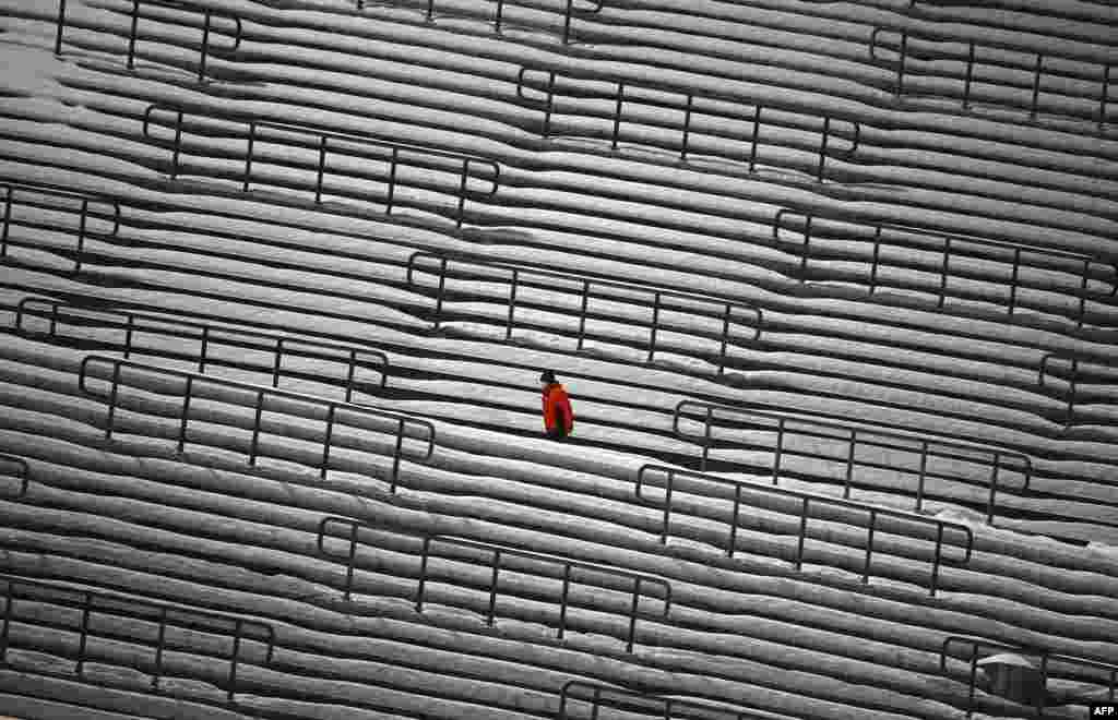 A ski jump staff member walks at empty stands during the second competition jump of the FIS Men's Ski Jumping World Cup in Willingen, western Germany, Jan. 30, 2021.