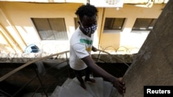 FILE - A visually impaired man climbs the stairs at a building where he lives, in Lagos, Nigeria, May 5, 2020.