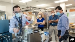 FILE - Astronaut Kate Rubins, center, and support personnel review the Universal Waste Management System, a low-gravity space toilet, in Houston, in this June 18, 2020, photo provided by NASA.