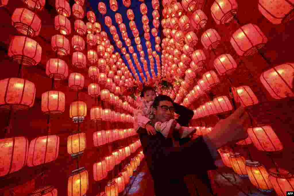 People take photos next to a display of lanterns decorated with lights during the Lantern Festival, which marks the end of the Lunar New Year celebrations in Taiyuan, in northern China's Shanxi province.