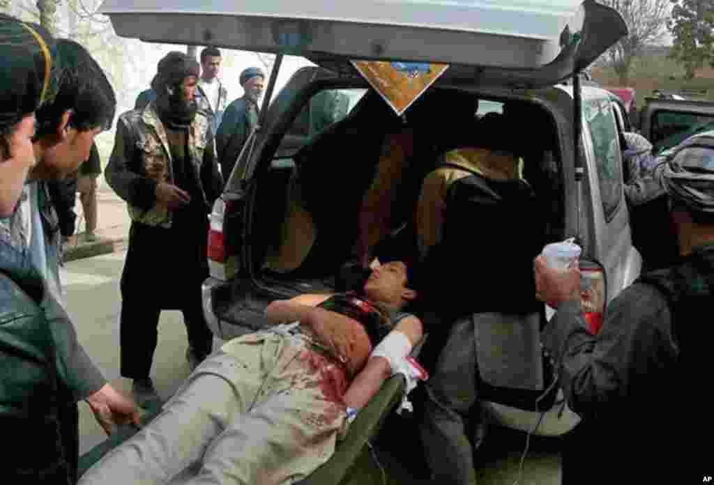 Afghans help an injured man into a vehicle after a suicide attack in Maimana, Faryab province, Afghanistan, March 18, 2014.