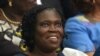 Simone Gbagbo, Ivory Coast's former first lady, smiles as she sits in the dock at the Court of Justice for the start of her trial in Abidjan, Ivory Coast, Dec. 26, 2014.