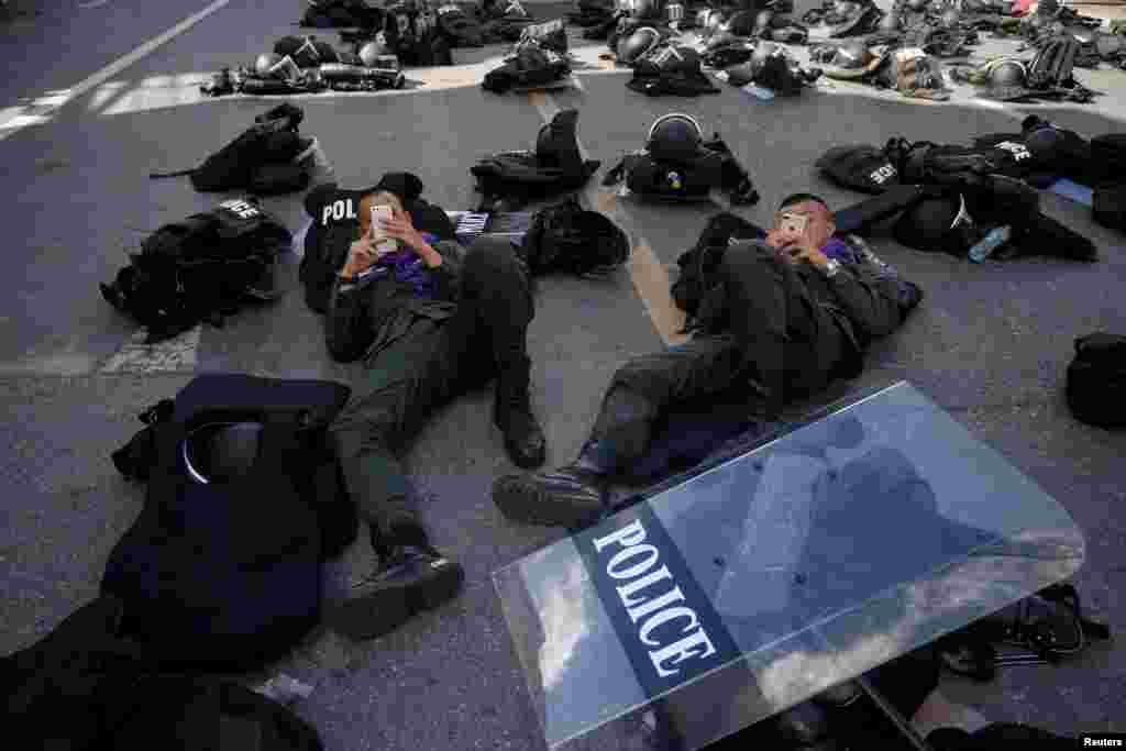 Police officers use their mobile phones near the Crown Property Bureau, ahead of a pro-democracy rally demanding Thailand's King Maha Vajiralongkorn hands back royal assets to the people and reforms on the monarchy, in Bangkok.