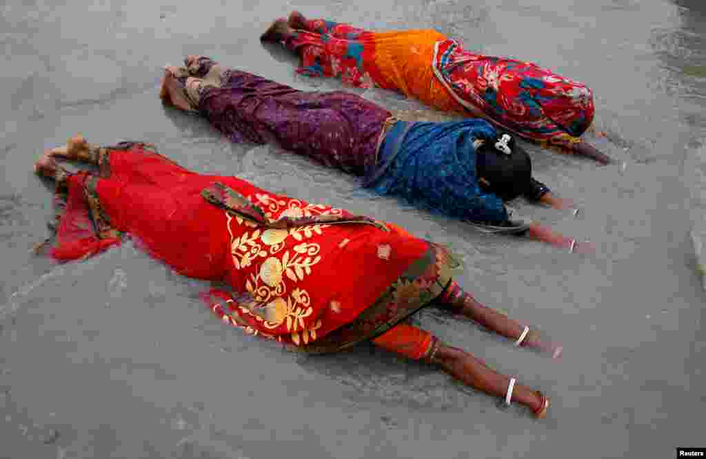Women worship to Hindu sun god as they take a dip at the confluence of the river Ganges and the Bay of Bengal on the occasion of "Makar Sankranti" festival at the Sagar Island in the eastern state of West Bengal, India.