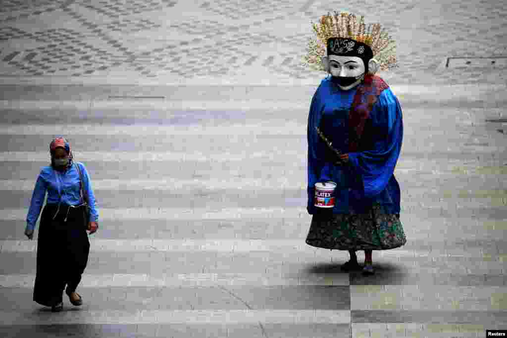 A traditional large puppet figure known as "Ondel-ondel", wearing a face mask, performs on a sidewalk in Jakarta, Indonesia.