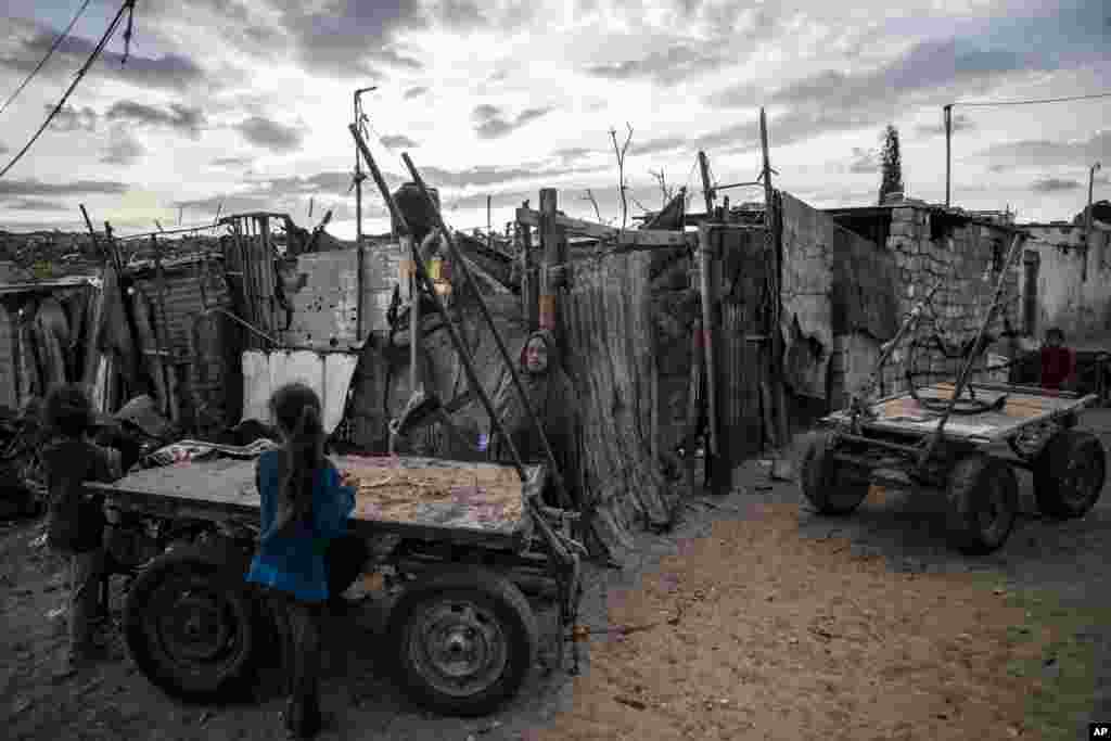 A Palestinian woman stands next to her house in a slum on the outskirts of Khan Younis Refugee Camp, in the southern Gaza Strip.