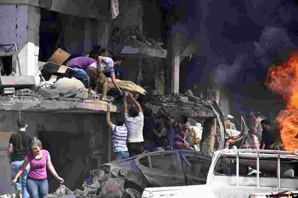 In this photo released by the Syrian official news agency SANA, Syrians carry the body of a victim from a building damaged in twin bombings struck Kurdish town of Qamishli, killing 44 people and wounding dozens more.